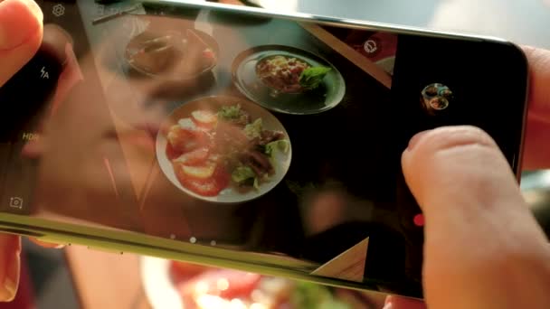 Meisje maakt een foto van de maaltijd op een smartphone in een café close-up — Stockvideo