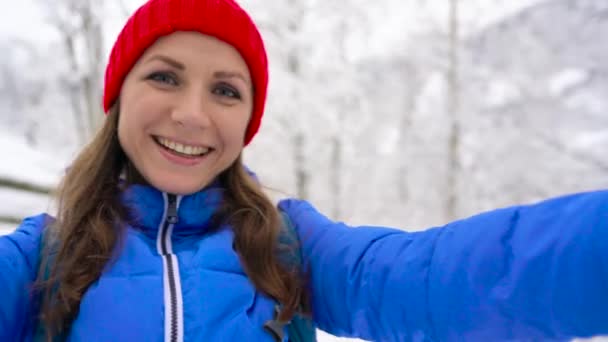 若い陽気な女性がカメラを保持し、雪に覆われた山の風景、カルパティア山脈に自分自身を撃つ — ストック動画