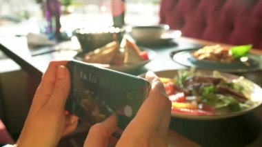 Kız bir fotoğraf yemek smartphone cep telefonu ile bir kafede yakın yapar