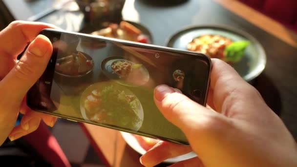 Meisje maakt een foto van de maaltijd op een smartphone in een café close-up — Stockvideo