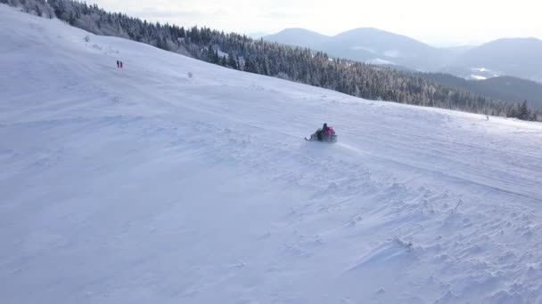 Vista desde la altura de las personas que conducen motos de nieve en la hermosa ladera nevada de la montaña. Clima frío claro — Vídeo de stock