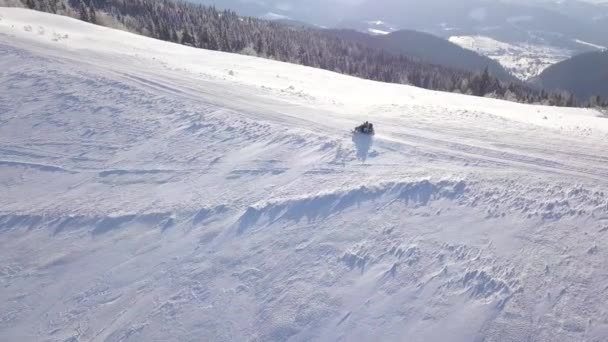 Uitzicht vanaf de hoogte op mensen het besturen van de sneeuwscooter op mooie besneeuwde berghelling. Duidelijk frosty weer — Stockvideo