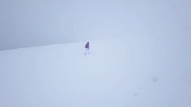 Uçuş bir dağın tepesine yürüyüş yalnız turist kız yüzünden karla kaplı. Rahatsız düşmanca kış hava.