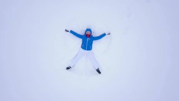 Aeriel vista desde el dron en la mujer haciendo ángeles de nieve y jugando en la nieve — Vídeo de stock