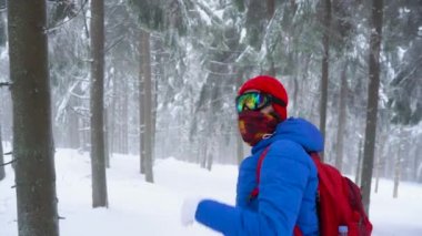 Turist kız arkadaşı için el sallayarak ve bir kış karla kaplı iğne yapraklı orman dağlarda yürüyüş. Soğuk hava