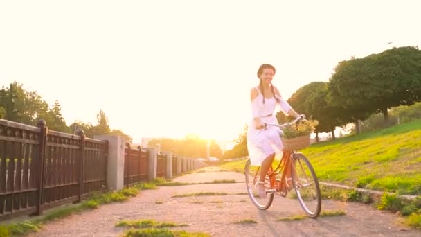 Junge schöne Frau auf einem Fahrrad bei Sonnenuntergang. Zeitlupe — Stockvideo