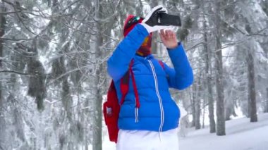 Yalnız turist kız kış karla kaplı iğne yapraklı bir ormanda dağlarda yürüyüş ve doğa fotoğrafı Smartphone'da alır. Soğuk hava
