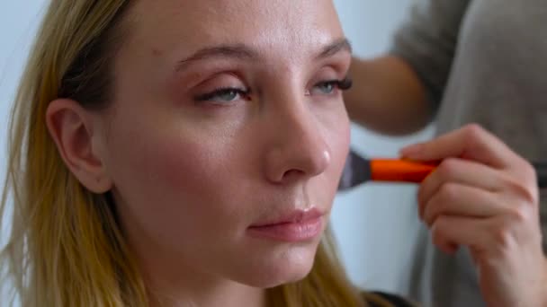 Make-up artist applica la polvere e rende la correzione della forma del viso alla ragazza — Video Stock