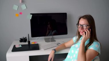 Yaratıcı ofiste bir kahve molası sırasında telefonda konuşurken rahat grafik tasarımcı