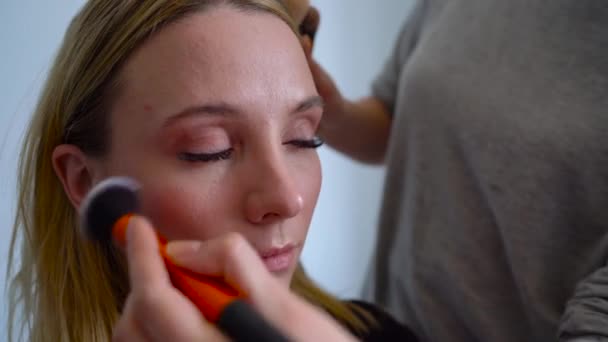 Make-up artist platí prášek a provede korekci tvaru obličeje k dívce — Stock video