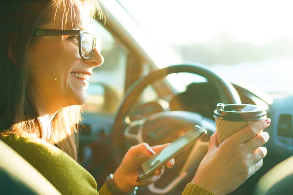 Donna che utilizza smartphone e bere caffè mentre seduto in un ca — Foto Stock