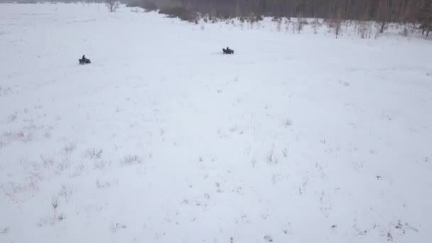 Uitzicht vanaf de hoogte van de ATV's rijden door het besneeuwde landschap in de winter — Stockvideo