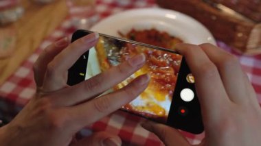 Kız bir fotoğraf yemek smartphone cep telefonu ile bir kafede yakın yapar