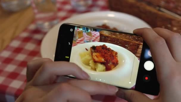 Meisje maakt een foto van de maaltijd op een smartphone in een café close-up — Stockvideo