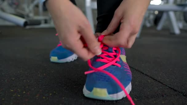 Zapatos de correr - mujer atando cordones de zapatos en el gimnasio — Vídeo de stock