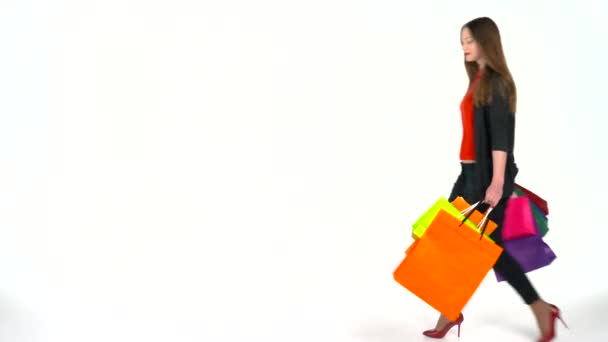 Mujer compradora sosteniendo bolsas de compras multicolores sobre fondo blanco en el estudio. Vamos a ir concepto de compras — Vídeo de stock