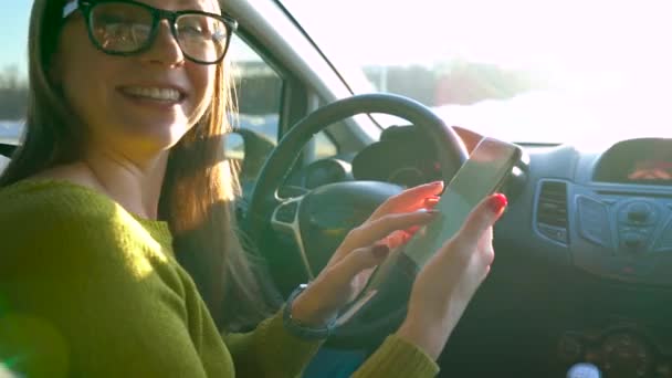 Mujer en gafas usando un smartphone y hablando con alguien en el coche — Vídeo de stock