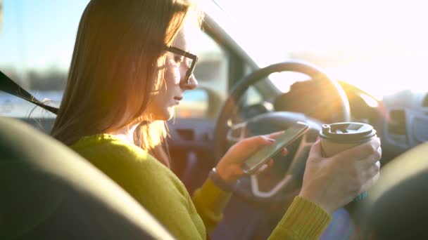 Kobieta w okularach za pomocą smartfona i napoje Kawa w samochodzie — Wideo stockowe