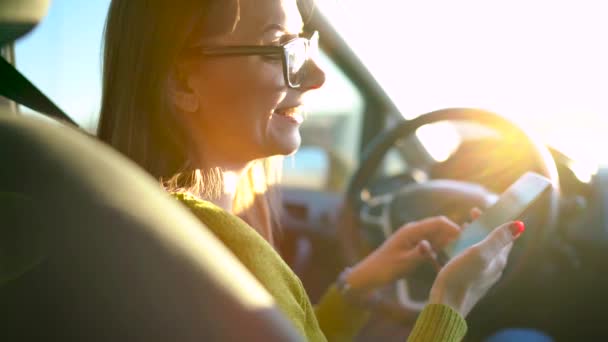 Mulher de óculos usando um smartphone no carro — Vídeo de Stock
