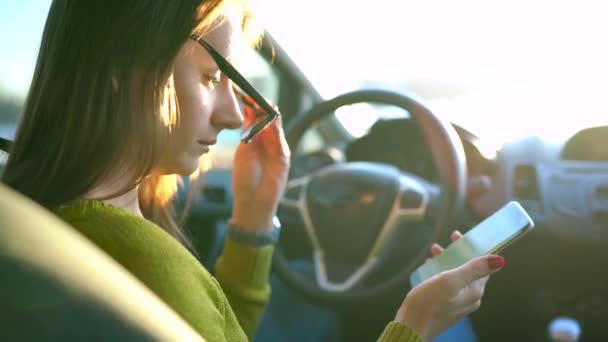 Frau mit Brille mit Smartphone im Auto — Stockvideo