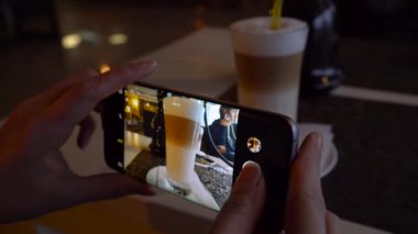 Kız bir latte fotoğrafını bir kafede bir akıllı telefon kadar yakın yapar