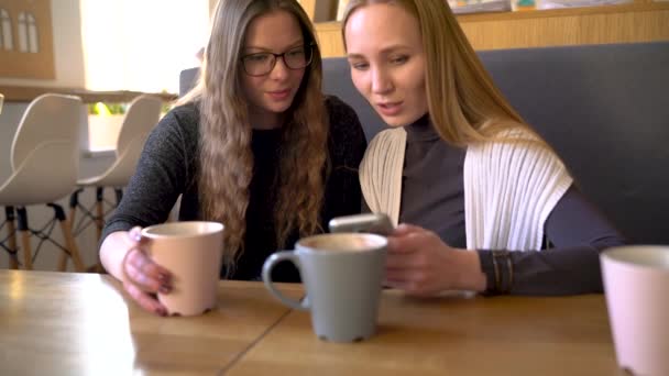 Cep telefonu kullaranarak kafede iki arkadaş kadın ve eğlenceli iletişim — Stok video
