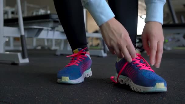 Běžecké boty - žena zavazování tkaniček v tělocvičně — Stock video