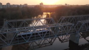 Demiryolu köprüsü üzerinde günbatımında tren geçiyor yükseklikten görüntülemek