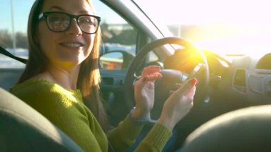 Bir smartphone kullanarak ve arabadan biri konuşurken gözlüklü kadın