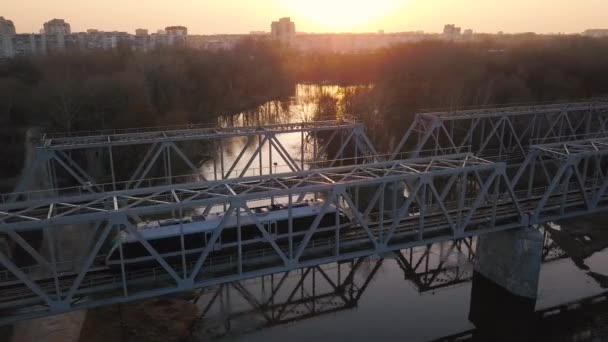 Вид з висоти залізничного мосту, на який поїзд проходить на заході сонця — стокове відео