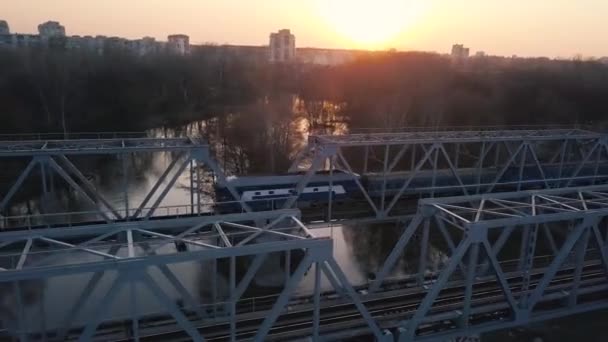 Uitzicht vanaf de hoogte van de spoorwegbrug waarop de trein bij zonsondergang is voorbij — Stockvideo