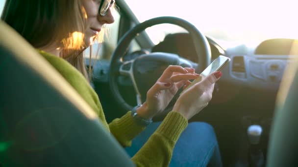 Frau mit Brille mit Smartphone im Auto — Stockvideo