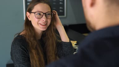 Genç çift kafede konuşuyor ve kahve içiyor.