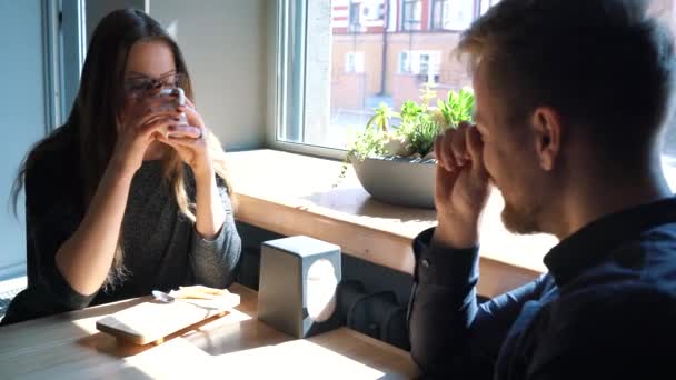 Νεαρό ζευγάρι μιλάει και πίνει καφέ στο καφέ — Αρχείο Βίντεο