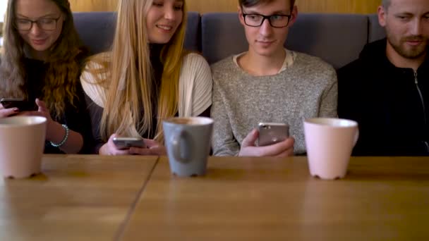 Grupp människor använder mobiltelefoner på ett kafé i stället för att kommunicera med varandra — Stockvideo