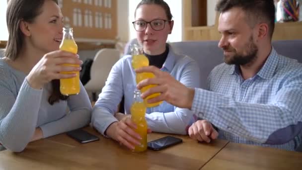 Drie vrienden zitten in een cafe, drink SAP en veel plezier bij het communiceren — Stockvideo