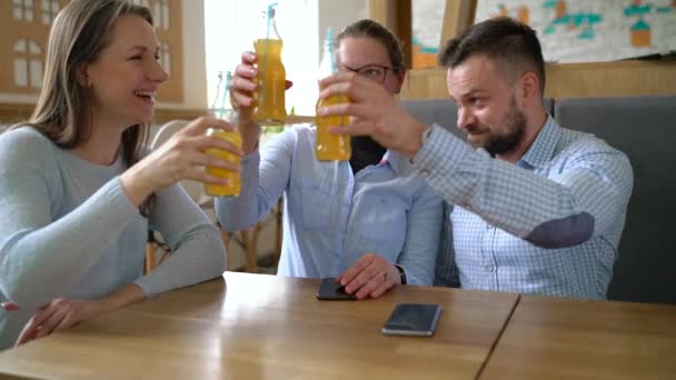 Trois amis s'assoient dans un café, boivent du jus et s'amusent à communiquer. Mouvement lent — Video