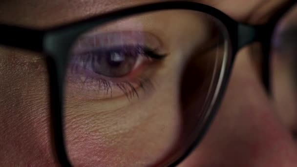 Kvinna i glasögon tittar på bildskärmen och surfar Internet. Skärmen återspeglas i glas — Stockvideo