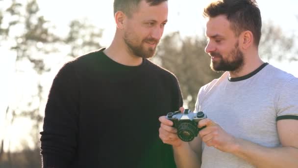 Giovani gay coppia scattare foto di se stessi su un film fotocamera in il primavera sera — Video Stock