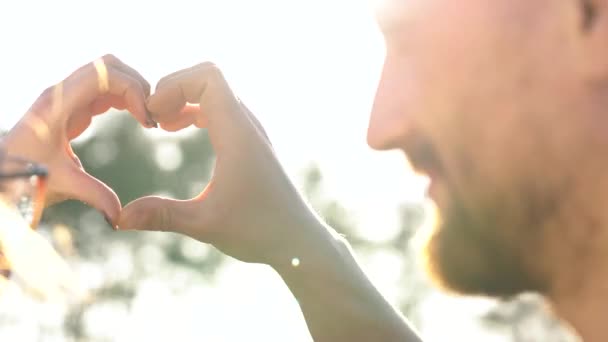 Jeune couple amoureux faisant symbole de coeur avec leurs mains au coucher du soleil — Video