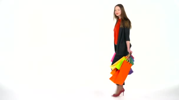 Vrouwelijke shopper veelkleurige boodschappentassen houden op witte achtergrond in de studio. Lets go shopping concept — Stockvideo