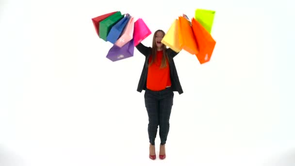 Mujer compradora sosteniendo bolsas de compras multicolores sobre fondo blanco en el estudio. Vamos a ir concepto de compras — Vídeos de Stock