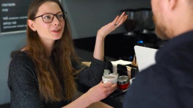 Genç çift kafede konuşuyor ve kahve içiyor.