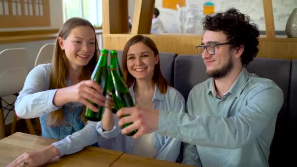 Drie vrienden zitten in een café, water of bier drinken en veel plezier bij het communiceren. Slow motion — Stockvideo