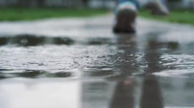 Yavaş çekim bacaklar bir koşucunun spor ayakkabı içinde kapatın. Çamurlu su birikintisi içine adım kadın spor adam açık havada bir parkta koşu.