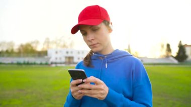 Kadın ve smartphone kablosuz kulaklık ile müzik seçer ve gün batımında stadyumun çalışır. Ağır çekim