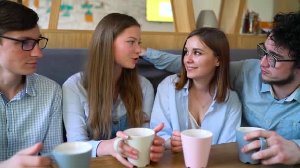 Jóvenes amigos se sientan en un café, toman café y se divierten comunicándose. Movimiento lento — Vídeos de Stock