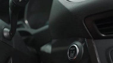 Erkek el, modern bir arabanın içinde motoru çalıştırma düğmesine basar.