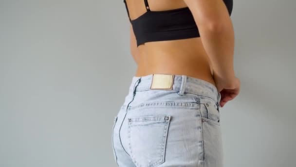 Vrouw kleedt zich uit, trekt jeans uit. Nauwelijks zichtbare cellulitis op de huid — Stockvideo