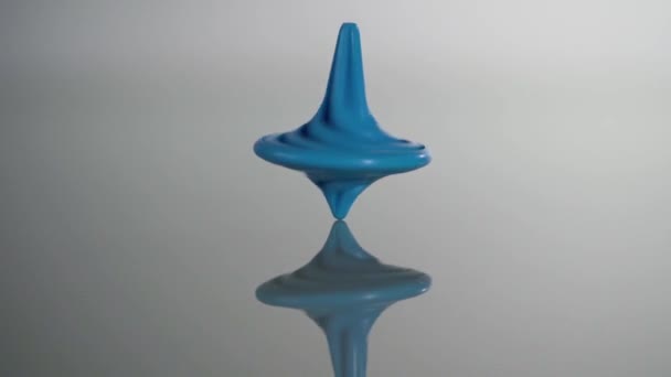 Blauw draaiende top draaiend, wiebelend en stoppend. Whirligig in actie wordt weerspiegeld op spiegeloppervlak — Stockvideo